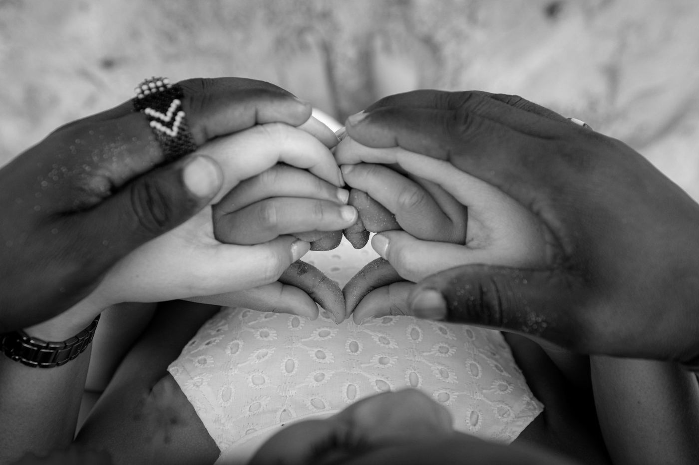 Hands of different skin tones joined together in a heart shape